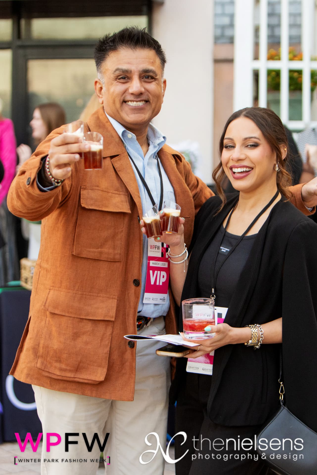 Two guests raising glasses in their VIP badges
