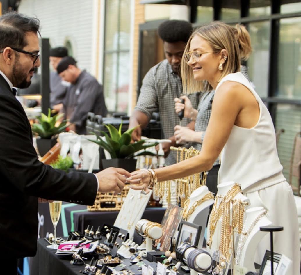 Guest trying on gold jewelry at a boutique market table