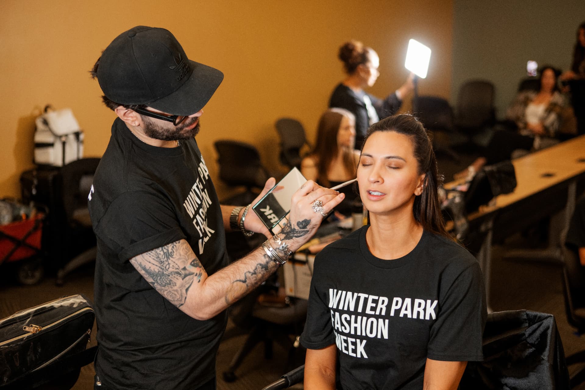 Makeup artist touching up a model backstage in a Winter Park Fashion Week tee