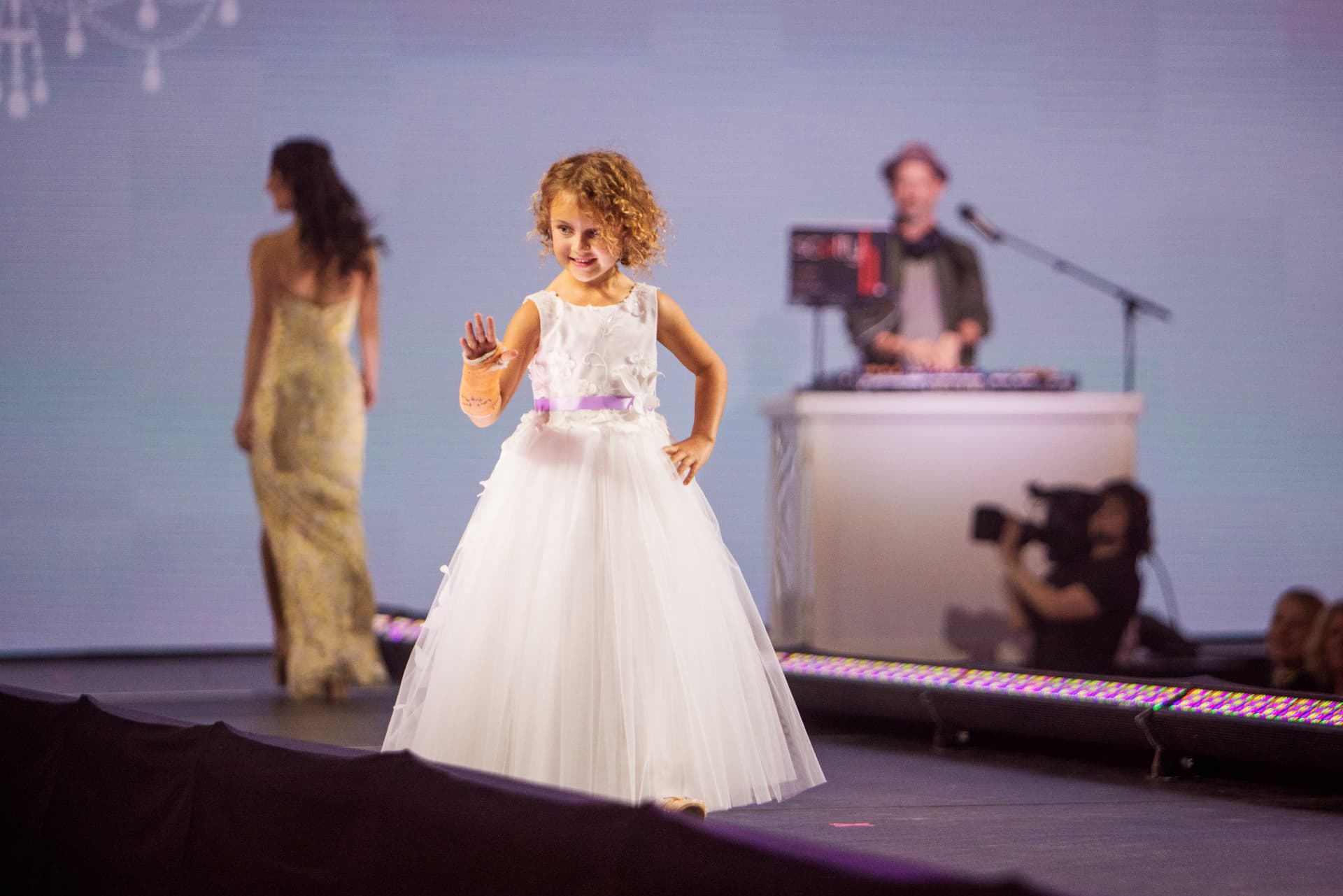 Young model in a white dress waving on the runway