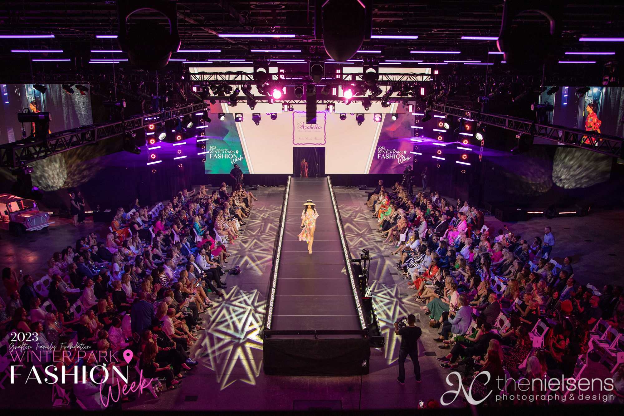Model in a straw hat and pastel floral look walking the runway for Arabella