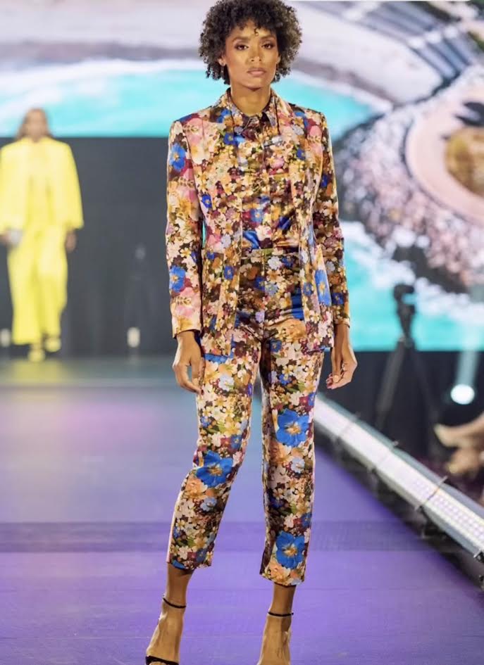 Model in a floral three-piece suit — blazer, shirt and trousers — walking the runway