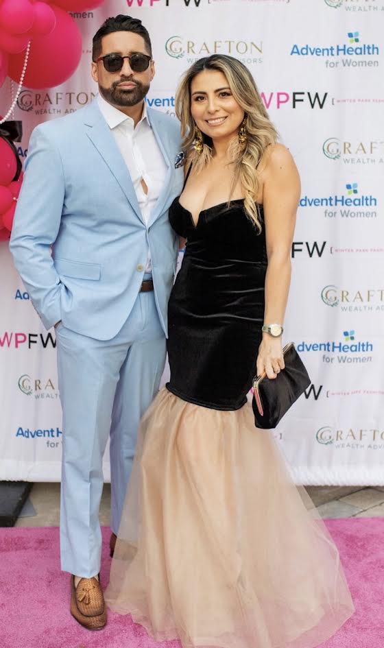 Couple in a light blue suit and a black velvet gown posing on the pink carpet